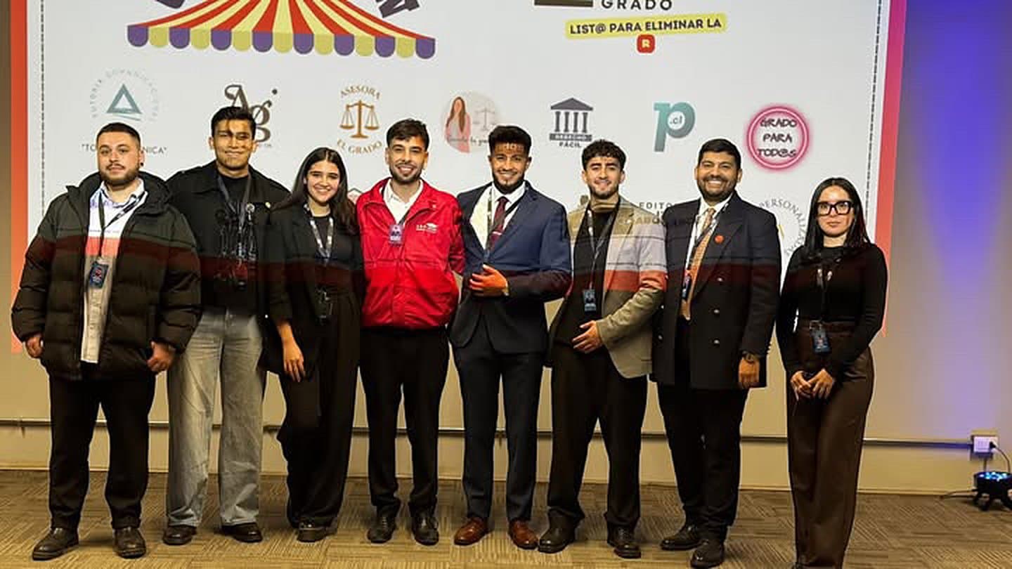 Grupo de expositores frente al panel de la Feria Expogrado, con el lema «List@ para eliminar la R»