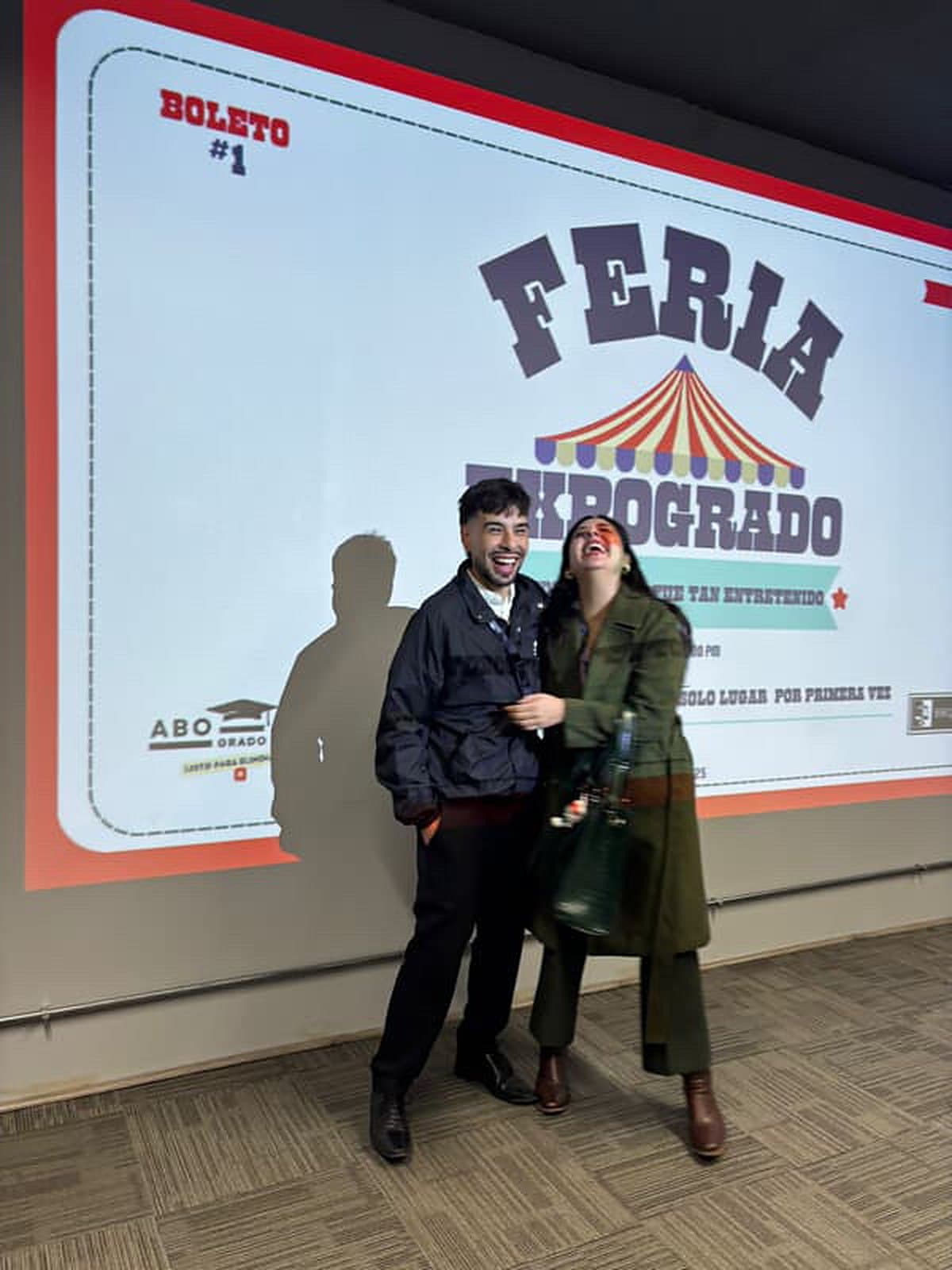Dos personas riendo frente a la pantalla de la Feria Expogrado